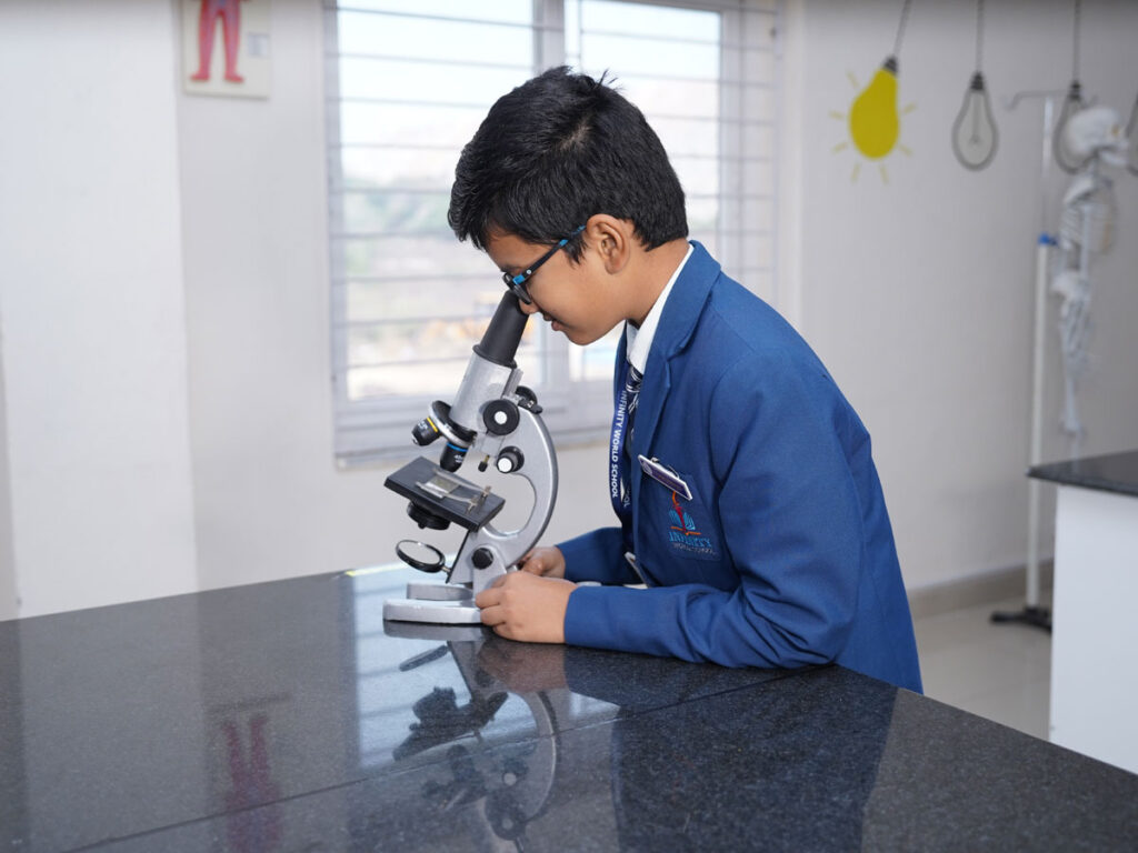 Kid exploring through a microscope at Infinity World School, a top CBSE and primary school in Chanda Nagar focused on hands-on learning.
